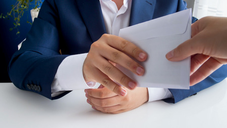 Closeup photo of pilitician receiving bribe in envelope