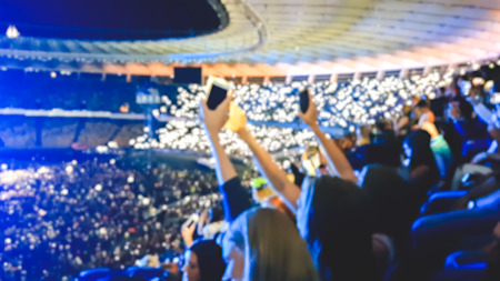 Defocused photo of big crowd of fans making image on smartphones and holding flashlights on the rock concert.の写真素材