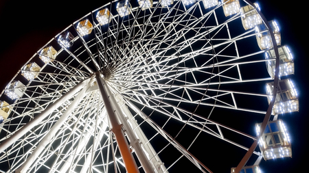 Beautiful photo of ferris wheel on city stret illuminated with white bulbs with night sky on the backgroundの写真素材