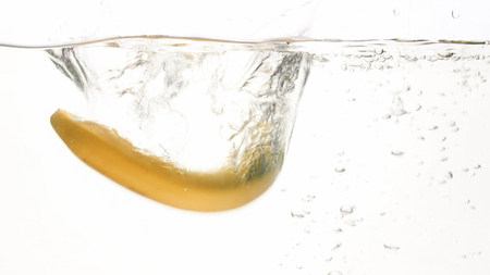 Closeup photo of fresh ripe bananas falling and splashing in water against white isolated backgroundの写真素材