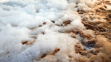 Closeup abstract photo of lots of soap foam after sea beach disco party lying on sandy shoreの写真素材