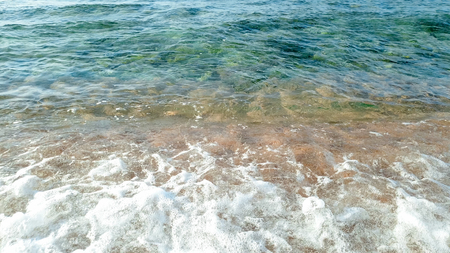 Closeup photo of calm sea waves rolling on wet sand at sea beachの写真素材
