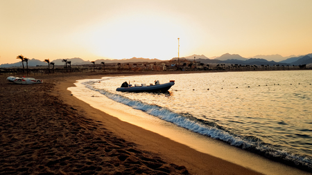 Beautiful photo of inflatable motorboat floating on sea waves against beutiful sunsetの写真素材