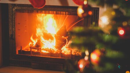 Beautiufl toned image of burning fireplace next to decorated Christmas tree with baubles and garlandsの写真素材
