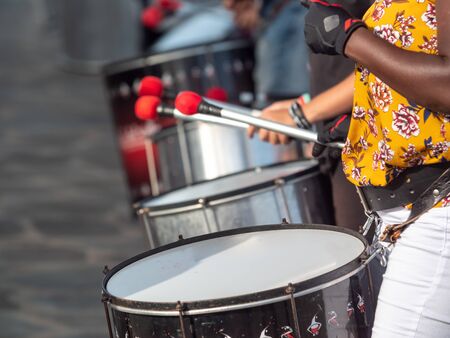 Closeup photo of african dark skin woman playing on drums during street performance