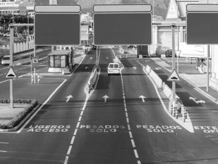 Black and white image of payment collecting post on busy highway with blank road signs, Place for...
