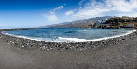 Beautiful panoramic photo of empty beach with volcanic black sand at sunny day. Tenerife, Canary islands, Spainの写真素材