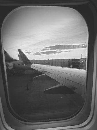 Black and white photo through airplane porthole on planes at airportの写真素材