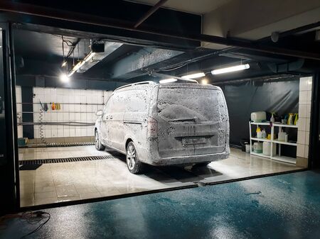 Big minivan car being washed with soap and foam on the carwash at garageの写真素材