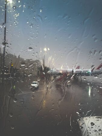 Toned image through water droplets on airplane porthole at airport terminalの写真素材