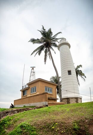 Old lighthouse building and coconut palm tree on the tropical islandの写真素材