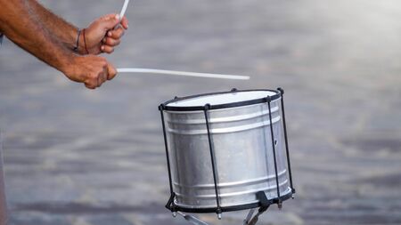 Closeup photo of male musician playing on drum with sticks