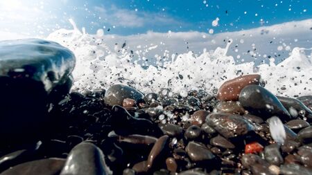 Closeup image of powerful ocean waves breaking and rolling tones and rocks on the sea beach.の写真素材