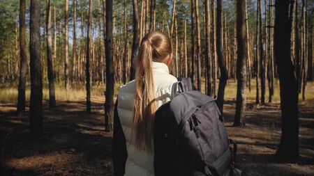 Toned photo of beautiful woman with backpack hiking in forest
