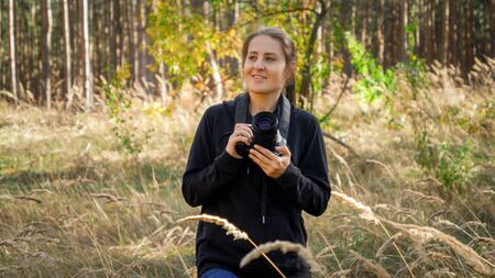 Portrait of beautfiul young woman with digital camera walking in wild forest