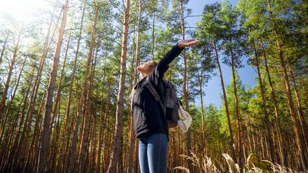 Portrait of smiling happy woman hiking in forest with outstretched hands . Concept of freedom and...