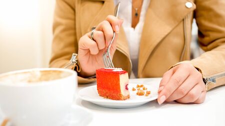 Closeup image of young woman eating dessert in cafe