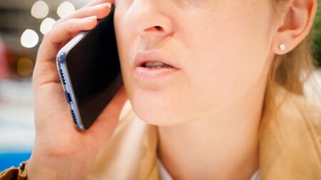 Closeup image of young beautiful woman talking by phone in cafe.