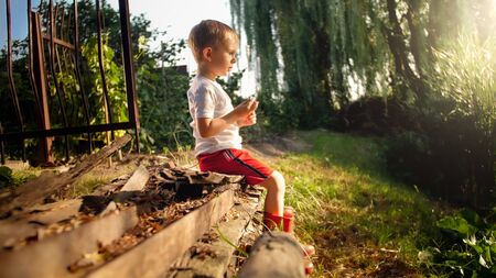 Little boy sitting at river and looking on the sunsetの写真素材