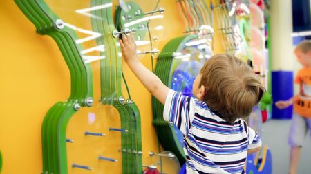 Cute little boy playing with educational mechanism in museum of science
