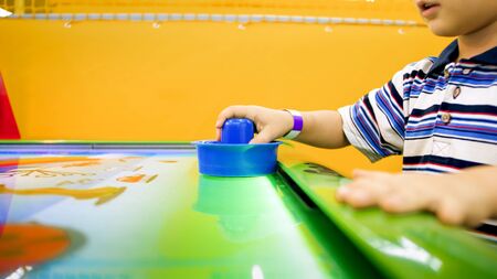 Closeup image of little boys hand playing in air hockey at shopping mallの写真素材