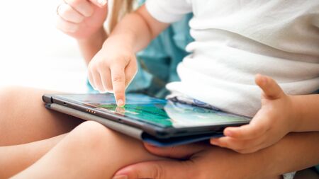 Closeup photo of little boy sitting at ome and using digital tablet computerの写真素材