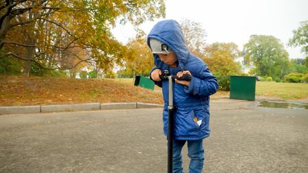 Portrait of sad and upset little boy riding on scooter at park