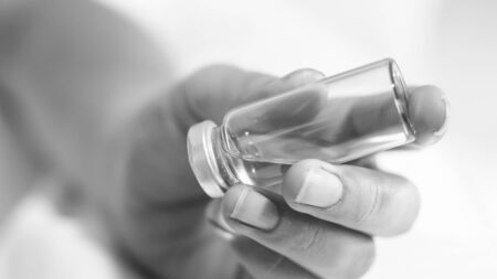 Black and white image of female nurse holding glass vial with medicines.の写真素材