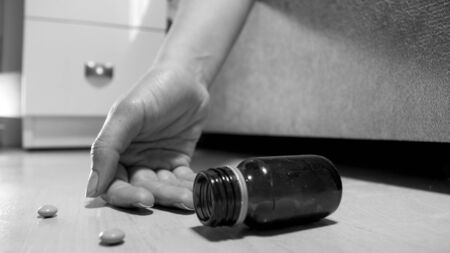 Hand of dead woman after suicide and pills lying on floor.の写真素材