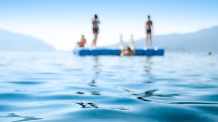 Blurred image of young people relaxing on pontoon in the sea.の写真素材