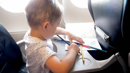 Little boy drawing picture on table in airplane.の写真素材