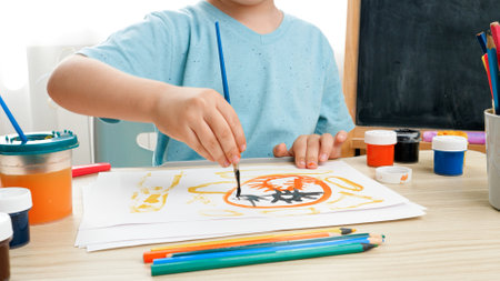 little boy prawing picture with colorful paint on white paper at domestic classroom. Creative child doing art painting. Education at home during lockdownの写真素材