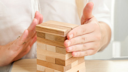 Closeup of businesswoman building high tower with wooden toy blocks and bricks. Concept of development, success and business growth.の写真素材