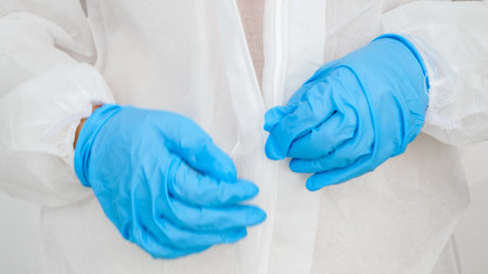 Closeup of female doctor wearing and zipping protective suit against viruses and biohard. Protection from covid-19 and coronavirus.の写真素材