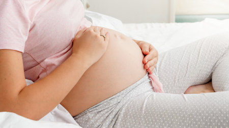 Closeup of pregnant woman gently stroking her belly. Concept of parenting and happy anticipation of...