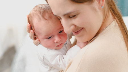 Closeup portrait of mothers and baby face against big window in bedroomの写真素材
