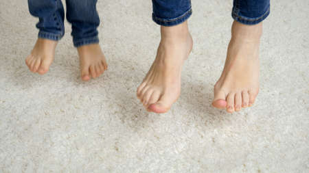 Closeup of mother and child feet jumping on soft carpetの写真素材