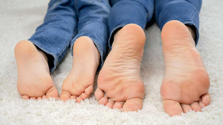 Closeup of child and parent feet lying on carpet