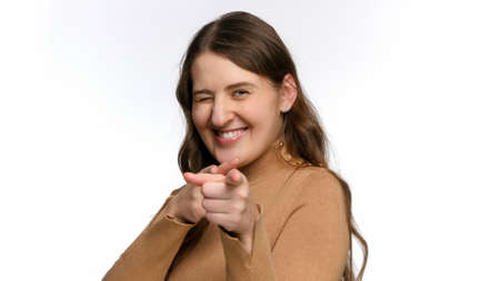 Portrait of smiling young woman aiming in you with fingers. Concept of success, winning and victory