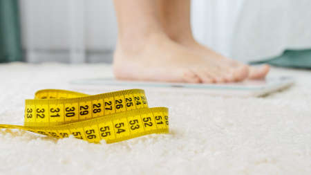 Closeup of yellow measuring tape lying next to digital scales. Concept of dieting, loosing weight...