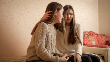 Teenage girl consoling and comforting her friend talking about her problems. Friends support and...