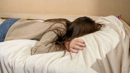 Crying teenage girl jumping on bed and lying on soft pillowの写真素材