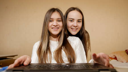 Two smiling girls using laptop and having online video call or conference. Remote work,...