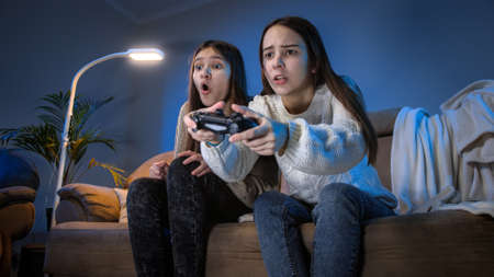 Happy laughing girls celebrating after victory in video game on console at night