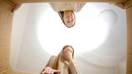 Two girls feeling disgusted after opening cardboard box and finding something miserable or stinky.の写真素材