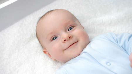 Portrait of happy smiling baby boy with blue eyes smiling on dressing table. Concept of hygiene,...