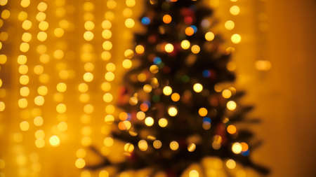 Out of focus shining Christmas tree. Glowing light garland. Perfect background for winter holidays and celebrationsの写真素材