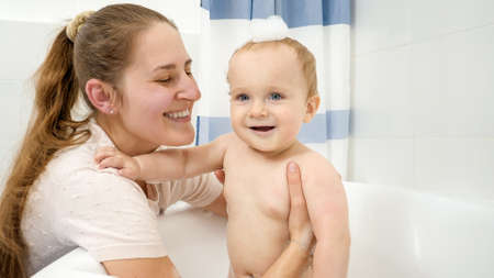 Portrait of happy smiling mother with baby boy having soap bath. Concept of children hygiene,...