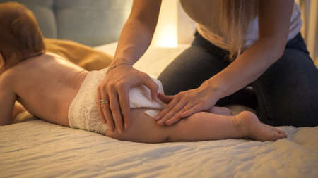 Closeup of mother applying and rubbin lotion or creme on her baby son. Concept of children hygiene, healthcare and family care at homeの写真素材