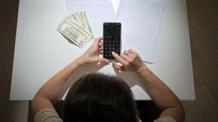 Top view of young woman gets upset after calculating mothly tax and house loan payment. Concept of financial difficulties, poverty, bankruptcy, taxes and rent payment.の写真素材